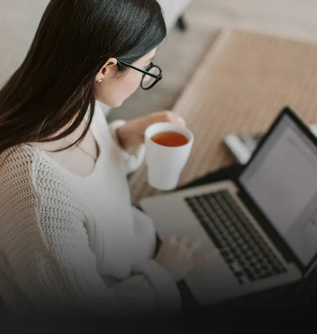 Una mujer trabajando desde su casa con una notebook y una taza de té